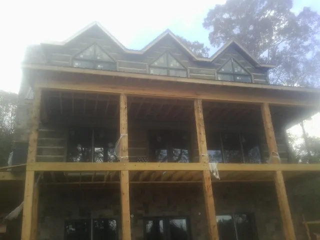 Dormers and porch framing on a large log home under construction — Roof Coating work by our crew in New Salem