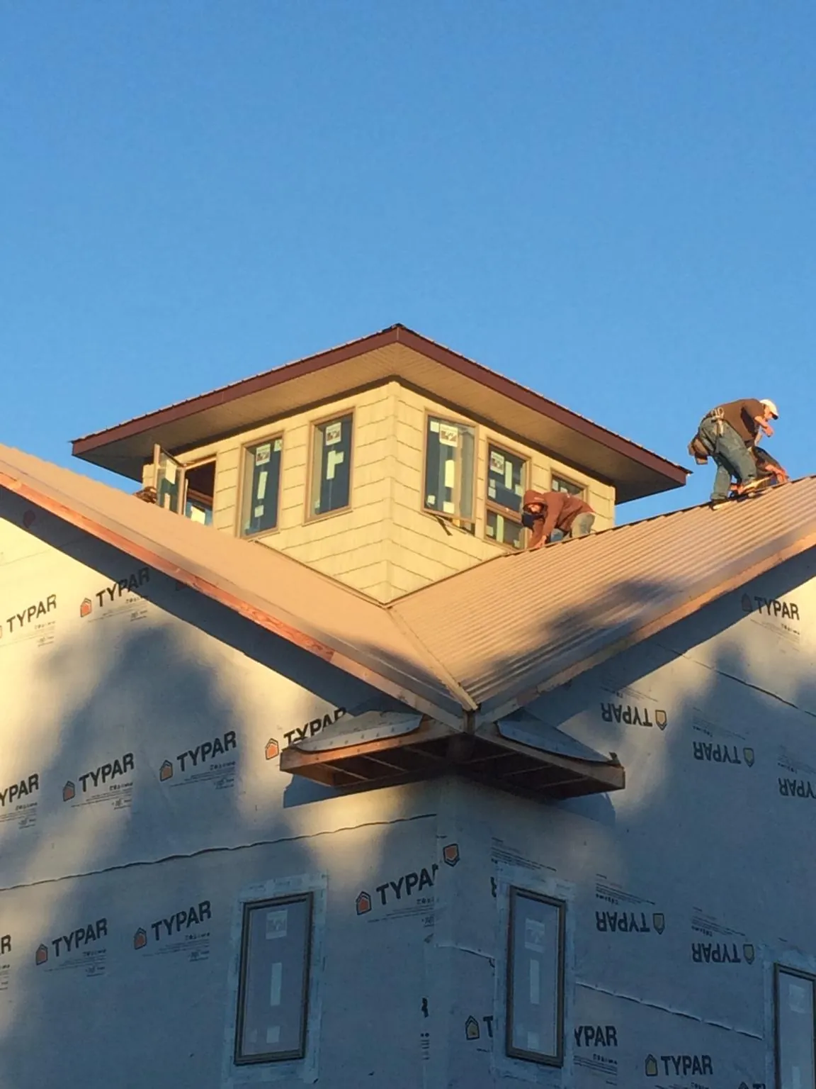 Roofers working around a rooftop cupola on a new metal roof at sunset — Roof Waterproofing in New Salem by Roofing Brothers